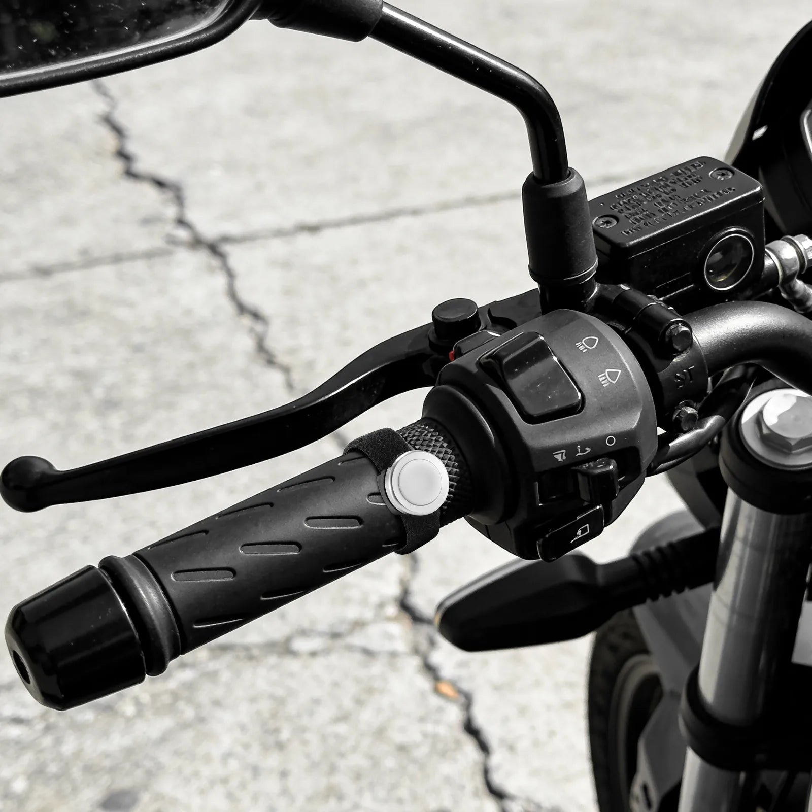 Close-up of motorcycle handlebar controls on a road background