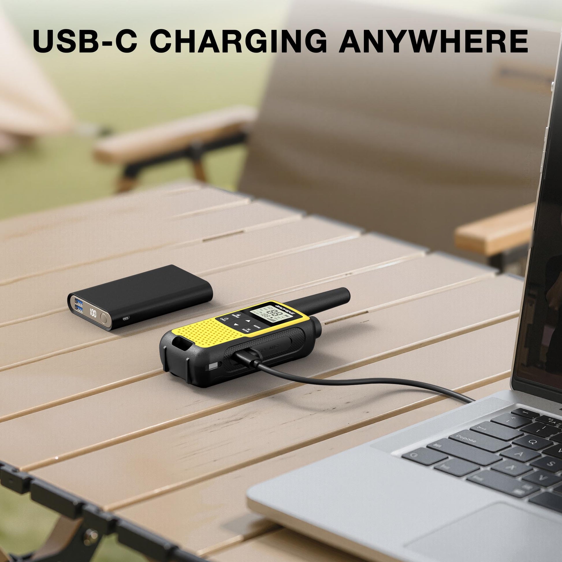 USB-C charging Baofeng BF-33C FRS/PMR Radio on a table with laptop and phone, outdoor setting.