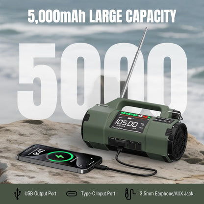 Green Raddy SH-907 Emergency Radio with charging phone on a rock by water, displaying 5000mAh capacity.