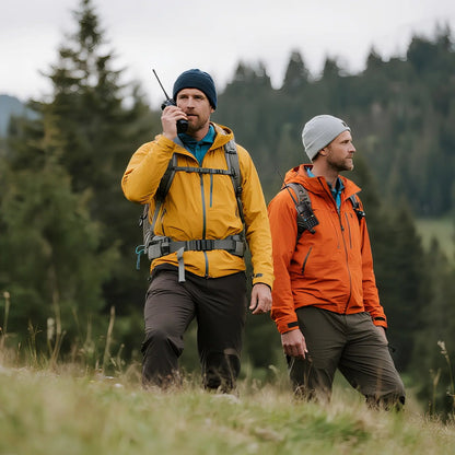 Two hikers in colorful jackets walking through a forested area.
