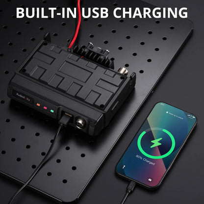 Black battery pack with USB cable connected to a smartphone on a black pegboard background.